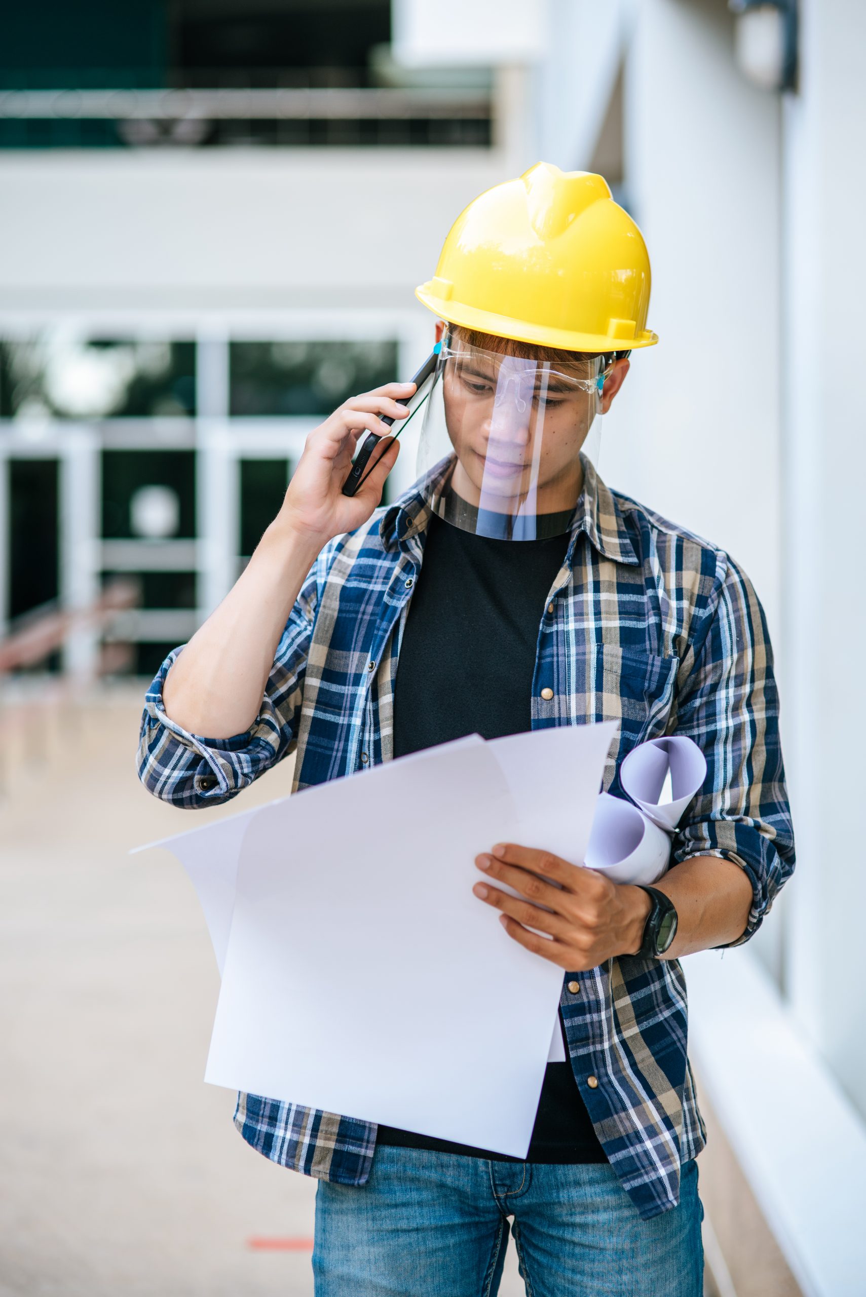 architects hold floor plans and talk on the phone.